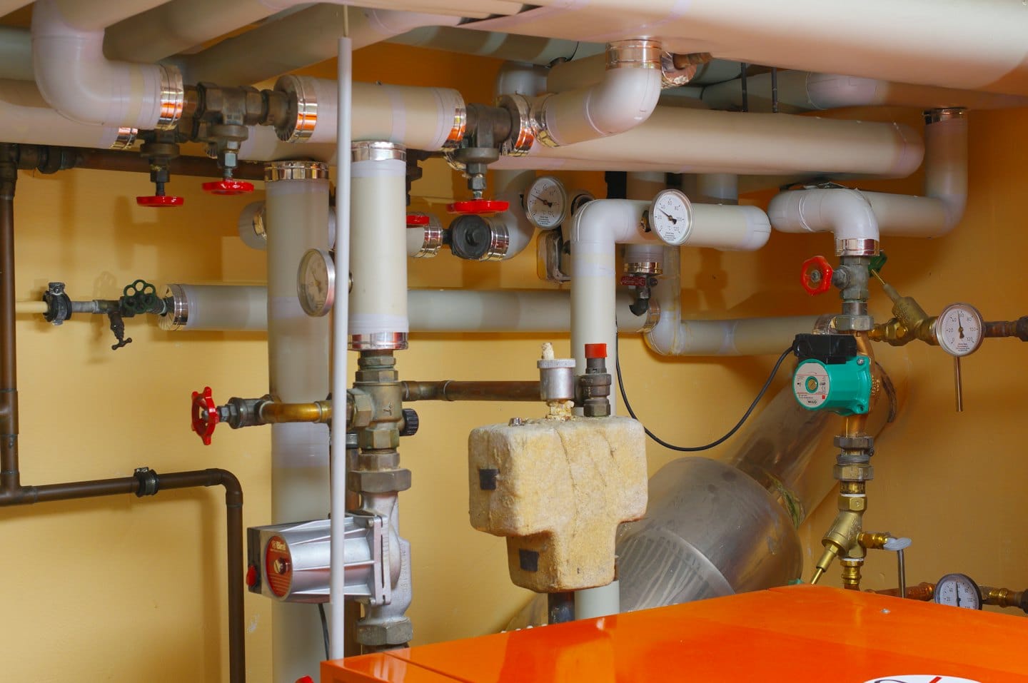 Rete di tubi, valvole e manometri in una sala tecnica.