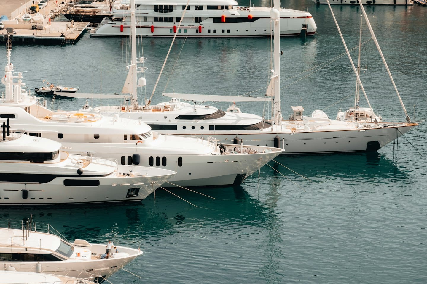 Yacht di lusso e barche a vela ormeggiati insieme in un vivace porto turistico.