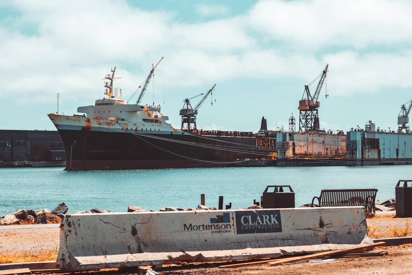 Grande nave industriale attraccata in un cantiere navale affollato con gru alte.